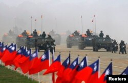 Tentara mengendarai kendaraan militer mereka melewati bendera Taiwan selama latihan militer di Hsinchu, Taiwan tengah. (Foto: Reuters)