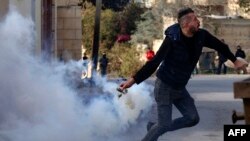 یک معترض فلسطینی هنگام پرتاب گاز اشک آوربه سوی نظامیان اسراییلی