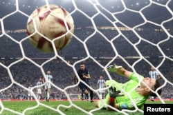 France's Kylian Mbappe scores their first goal from the penalty spot past Argentina's Emiliano Martinez.