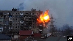 Sebuah ledakan terlihat di sebuah gedung apartemen setelah ledakan dari tank tentara Rusia di Mariupol, Ukraina, 11 Maret 2022. (Foto: AP)