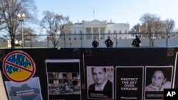 Foto-foto mereka yang tewas, termasuk jurnalis Brent Renaud, dipajang di pagar selama protes terhadap invasi Rusia ke Ukraina di Lafayette Park dekat Gedung Putih, Minggu, 13 Maret 2022, di Washington. (Foto: AP) 