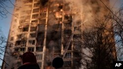 Petugas pemadam kebakaran Ukraina sedang berusaha memadamkan api di sebuah gedung apartemen setelah pemboman di Kyiv, Ukraina, Selasa, 15 Maret 2022. (Foto: AP/Felipe Dana)
