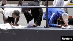 FILE - Abadabuka eZimbabwe balungisa amaphepha okuhlala lokusebenza kwele South Africa.