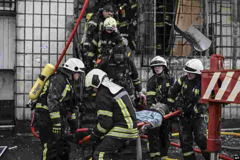 Zjarrfikësit largojnë trupin e një gruaje që vdiq në apartmentin e saj të shkatërruar pas bombardimeve në Kiev, më 15 mars 2022, në sulmet që shkaktuan vdekjen e të paktën dy personave, njoftojnë shërbimet urgjente ukrainase. Një seri shpërthimesh të fuqishme goditën zonat e banimit në Kiev, pak orë para vazhdimit të bisedimeve midis Ukrainës dhe Rusisë. 