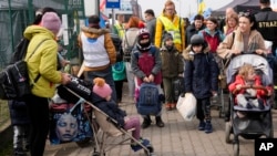 FILE - Ukrainian refugees depart from the border crossing in Medyka, southeastern Poland, March 30, 2022.