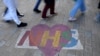 FILE - Shoppers walk past artwork denoting appreciation for the U.K. National Health Service, on Oxford Street in London, Oct. 20, 2021