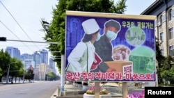 Sebuah papan iklan menggambarkan pengiriman produk-produk medis di sebuah jalan yang sepi di tengah ketakutan penyebaran COVID-19 di Pyongyang, Korea Utara. Foto dirilis oleh kantor berita Kyodo pada 23 Mei 2022. (Foto: Kyodo via Reuters)