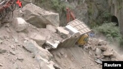 Foto dari tangkapan layar menunjukkan sebuah alat berat memindahkan puing-puing di sekitar kendaraan yang terjebak setelah runtuhnya terowongan yang sedang dibangun di Ramban, Jammu, dan Kashmir, Jumat, 20 Mei 2022. (Foto: ANI via Reuters)
