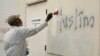 FILE - A man paints over racist graffiti on the side of a mosque in what officials were calling an apparent hate crime, in Roseville, Calif., Feb. 1, 2017.
