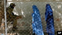 Seorang anggota Taliban berjaga-jaga ketika dua perempuan memasuki kantor paspor pemerintah, di Kabul, Afghanistan, 27 April 2022. (Foto: AP)
