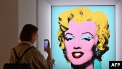 A woman takes a photo of Andy Warhol's 'Shot Sage Blue Marilyn' during Christie's 20th and 21st Century Art press preview at Christie's New York on April 29, 2022, in New York City.
