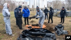 Tim investigasi forensik Prancis, yang tiba di Ukraina untuk menyelidiki dugaan kejahatan perang, beridir di dekat kuburan massal di Kota Bucha, Ukraina, pada 12 April 2022. (Foto: AP/Wladyslaw Musiienko)
