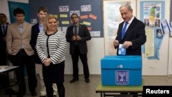 Israel's Prime Minister Benjamin Netanyahu (R) casts his ballot for the parliamentary election as his wife Sara (3rdL) stands nearby at a polling station in Jerusalem, January 22, 2013.