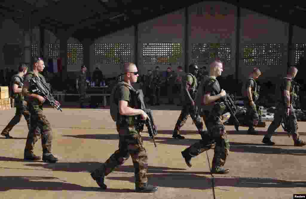 French soldiers walk past a hangar they are staying at the Malian army air base in Bamako, January 14, 2013.