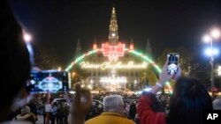 Para pengunjung mengambil foto iluminasi di Wiener Chritkindlmarkt, salah satu pasar Natal paling populer di Wina, Austria, Sabtu, 19 November 2022. (AP/Michael Gruber)