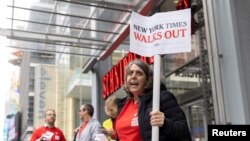 A guild member holds a placard supporting a union walk-out, outside the New York Times building in Manhattan, New York, Dec. 8, 2022.