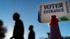 Voters pass a sign outside a polling site in Warwick, R.I., Nov. 7, 2022, after casting their ballots on the last day of early voting before the midterm election.