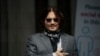 Aktor AS Johnny Depp memberi isyarat kepada penggemar dan media saat ia tiba di Pengadilan Tinggi di London, Kamis, 23 Juli 2020. (Foto: AP)