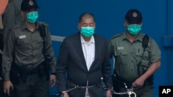FILE - Hong Kong Hong Kong media mogul and pro-democracy activist Jimmy Lai, is escorted by Correctional Services officers to get on a prison van before appearing in a court in Hong Kong, Dec. 12, 2020.