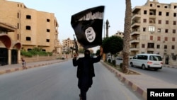 Seorang pendukung ISIS dan ISIL di Irak membawa bendera ISIL di Raqqa, 29 Juni 2014. (Foto: Reuters/arsip)