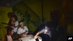 Warga Kuba bermain domino dengan senter saat listrik padam pasca badai Ian di ibu kota Havana, Rabu, 28 September 2022.