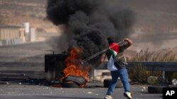 Seorang pedemo Palestina menggunakan ketapel saat bentrokan dengan tentara Israel di Kota Ramallah, Tepi Barat, 20 Oktober 2022. (Foto: Nasser Nasser/AP Photo)