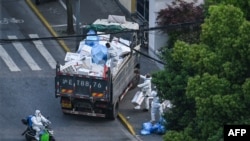 Pekerja kebersihan mengenakan alat pelindung diri (APD) selama lockdown COVID-19 di distrik Jing'an di Shanghai pada 20 April 2022. (Foto: AFP/Hector Retamal)