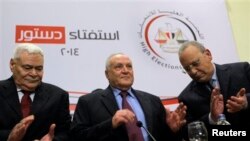 Judge Nabil Salib, head of Egypt's High Election Commission, center, is greeted by fellow commissioners as he prepares to announce voting results of referendum on military-backed constitution, Cairo, Jan. 18, 2014.