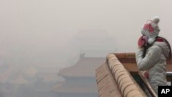 A woman adjusts her mask during a heavily polluted day in Beijing Tuesday, Dec. 22, 2015.