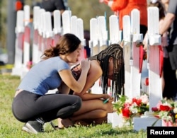A senior at Marjory Stoneman Douglas High School weeps in front of a cross and Star of David for shooting victim Meadow Pollack while a fellow classmate consoles her at a memorial by the school in Parkland, Florida, Feb. 18, 2018.