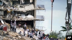 Rescue workers search in the rubble at the Champlain Towers South condominium, June 28, 2021, in the Surfside area of Miami.