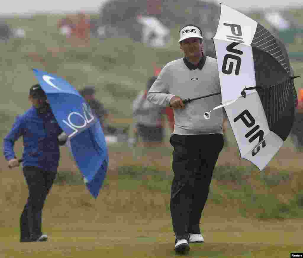 Bubba Watson of the U.S. and Northern Ireland's Rory McIlroy use umbrellas to shelter from the rain on the 14th hole during the second round of the British Open at Royal Troon, Scotland, Britain.