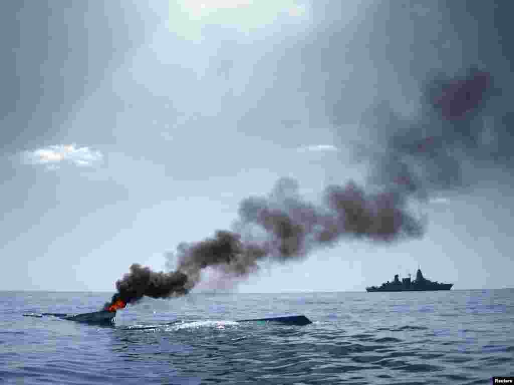 As part of the EU Naval Force Somalia, the German Frigate 'Hamburg' patrols after destroying two fishing boats (L) which were discovered floating keel side up in open waters off the coast of Somalia, August 15, 2011.