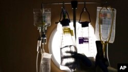 FILE - A nurse manager checks on IV fluids while talking to a COVID-19 patient at Providence Holy Cross Medical Center in Los Angeles, Dec. 13, 2021. 