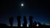 FILE - The moon shines above a group of people on the lookout for unidentified flying objects tour in the desert outside Sedona, Arizona, Feb. 14, 2013. 