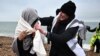 FILE - Volunteers from the refugee crisis charity Care4Calais gives a migrants, picked up at sea attempting to cross the English Channel, a dry blanket at Dungeness on the southeast coast of England, on December 9, 2022. 