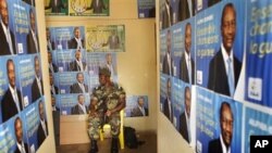 A soldier sits amidst election posters of Presidential candidate Alpha Conde in the entrance of the Guinean People Rally (RPG) headquarters in Guinea's capital Conakry Saturday 18 Sept. 2010
