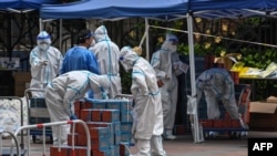 Pekerja mengenakan alat pelindung diri (APD) memeriksa makanan yang dikirim oleh pemerintah setempat untuk warga di kompleks selama lockdown karena COVID-19 di distrik Jing'an di Shanghai, China, 10 April 2022. (Foto: AFP)