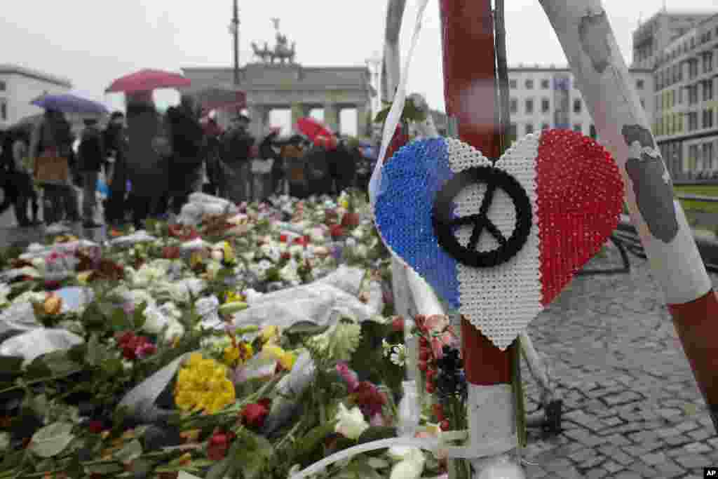 Bunga dan lilin untuk para korban serangan maut di Paris terlihat di depan Kedutaan Besar Perancis dekat Gerbang Brandenburg di Berlin, Jerman (15/11). (AP/Markus Schreiber)