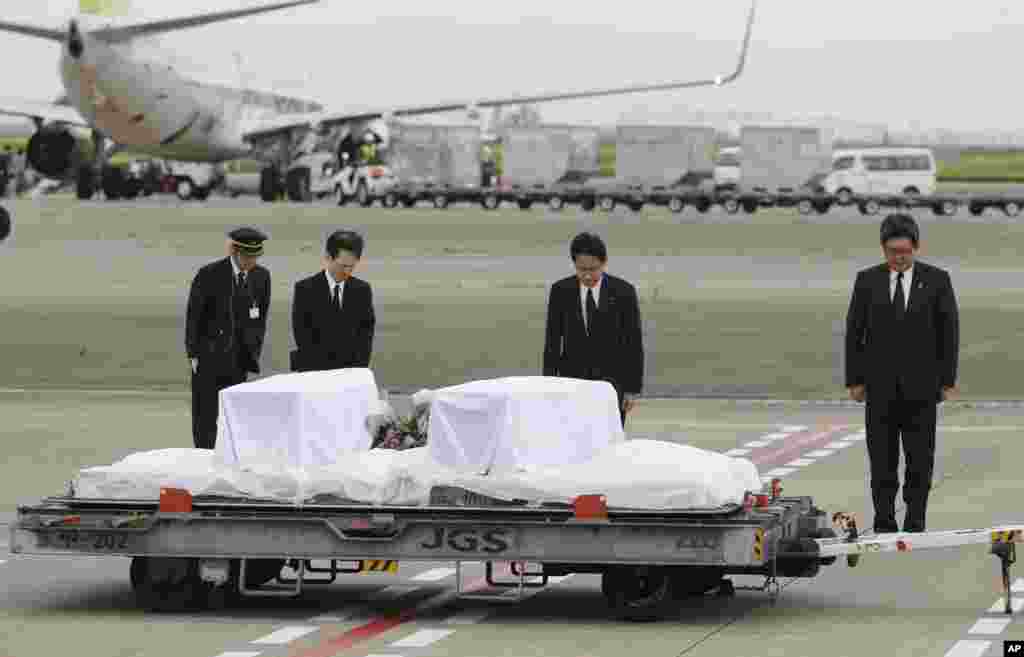 Japanese Foreign Minister Fumio Kishida, second right, bows in front of the coffins of victims in a weekend attack on a restaurant in Bangladesh, at Haneda Airport in Tokyo as they returned. Seven Japanese were killed in the attack.