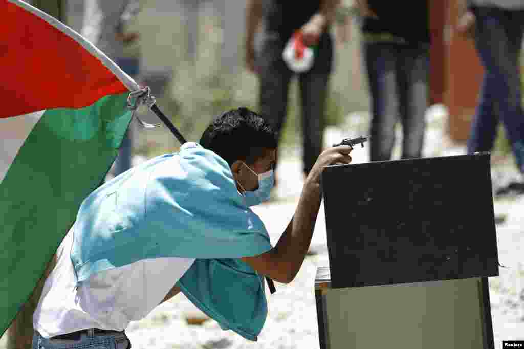 A Palestinian protester uses a toy gun during clashes with Israeli troops over the controversial Israeli barrier in Kfar Aqab near the West Bank city of Ramallah.