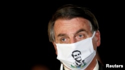 FILE - Brazil's President Jair Bolsonaro speaks with journalists while wearing a protective face mask as he arrives at Alvorada Palace, amid the coronavirus disease (COVID-19) outbreak, in Brasilia, Brazil.