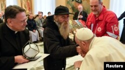 Paus Fransiskus mencium tangan seorang pria saat bertemu delegasi Penghargaan Bunda Teresa sekaligus perayaan ulang tahunnya yang ke-86 di Vatikan, Sabtu, 17 Desember 2022. (Foto: Vatican Media via Reuters)