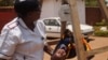 FILE - Charity Salima weighs a child at Achikondi Community Clinic in Lilongwe, Malawi. Malawi's nurses' union wants to allow nurses to work abroad. (Lameck Masina/VOA)