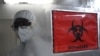 Seorang petugas kesehatan mengenakan alat pelindung diri (APD) berjalan melewati tanda biohazard di dalam fasilitas laboratorium molekuler yang disiapkan untuk menguji penyakit cacar monyet sebagai ilustrasi. (Foto: AFP)