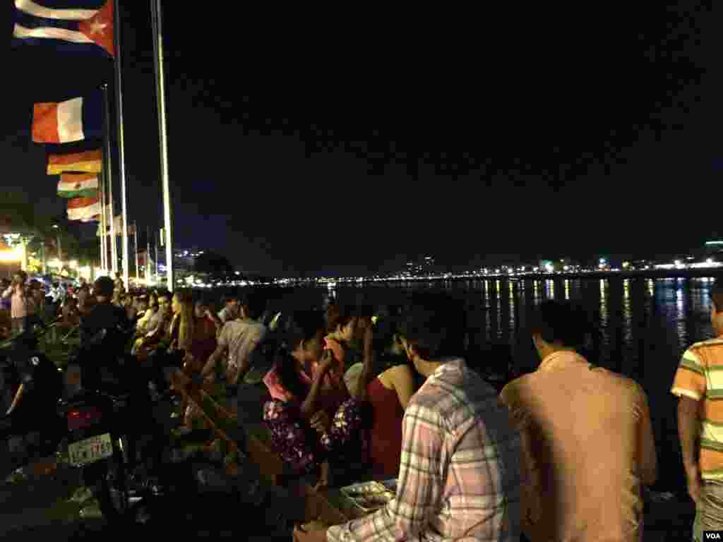 អ្នកទស្សនាអង្គុយនៅតាមដងទន្លេចតុមុខមើលទៅទន្លេដែលពំុមានប្រទីបនិងទូកងទេ។ ទិដ្ឋភាពនៅមុខព្របរមរាជវាំងនៅថ្ងៃចុងក្រោយនៃពិធីបុណ្យអំុទូក កាលពីថ្ងៃទី២៦ ខែវិច្ឆិកា ឆ្នាំ២០១៥។ (ផន បុប្ផា/VOA)