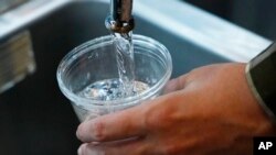 FILE - A cup of water is drawn from a faucet at Johnny T's Bistro and Blues, a midtown Jackson, Miss., restaurant and entertainment venue, Sept. 1, 2022. Although it is no longer cloudy, owner John Tierre said he has concerns over the city's longstanding 