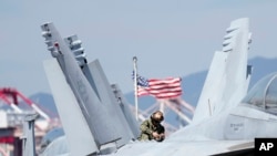 Tentara AS memeriksa jet tempur F/A-18 Super Hornet di geladak kapal induk bertenaga nuklir USS Ronald Reagan di Busan, Korea Selatan, 23 September 2022. (Foto: AP)