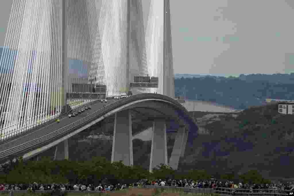 Spectators watch as the cortege with the hearse carrying the coffin of Queen Elizabeth II crosses the Queensferry Bridge as it makes its journey to Edinburgh from Balmoral in Scotland, Sept. 11, 2022.