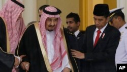 Indonesian President Joko Widodo, right, assists Saudi King Salman, center, to walk during their meeting at the presidential palace in Bogor, West Java, Indonesia, Wednesday, March 1, 2017.